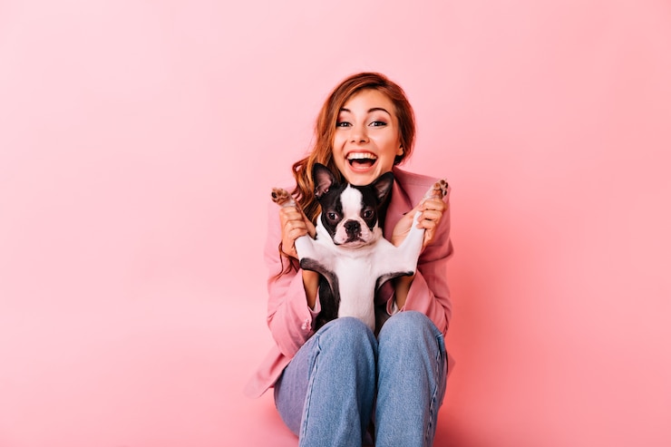 Foto grátis que bom que garota de jeans brincando com um cachorrinho engraçado. retrato interno da senhora ruiva animada com penteado encaracolado, passando um tempo com seu cachorro.