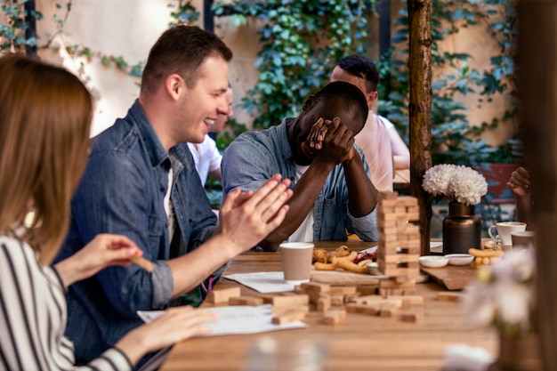 Quebrando a torre jenga e rindo com os melhores amigos no acolhedor restaurante ao ar livre