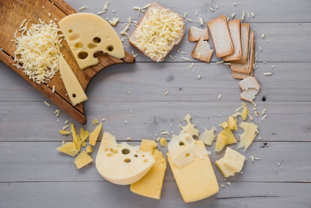 Queijo ralado com fatias e pão na mesa de madeira cinza