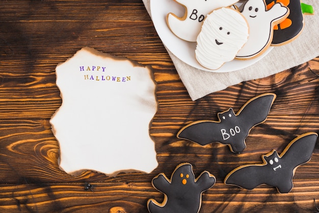 Foto grátis queima de papel perto de pão de gengibre de halloween na placa