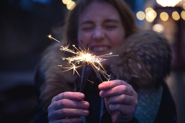 Queimando fogos de artifício nas mãos de uma jovem no escuro