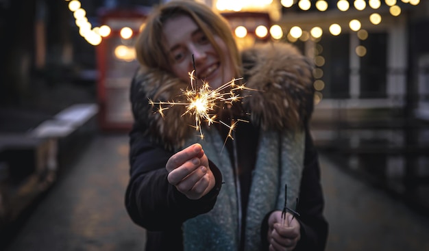 Queimando fogos de artifício nas mãos de uma jovem no escuro