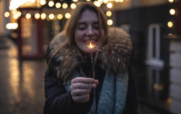 Queimando fogos de artifício nas mãos de uma jovem no escuro