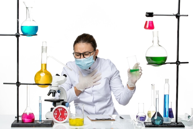 Química feminina de frente para o terno médico com máscara segurando a solução no fundo branco respingo laboratório vírus química covid