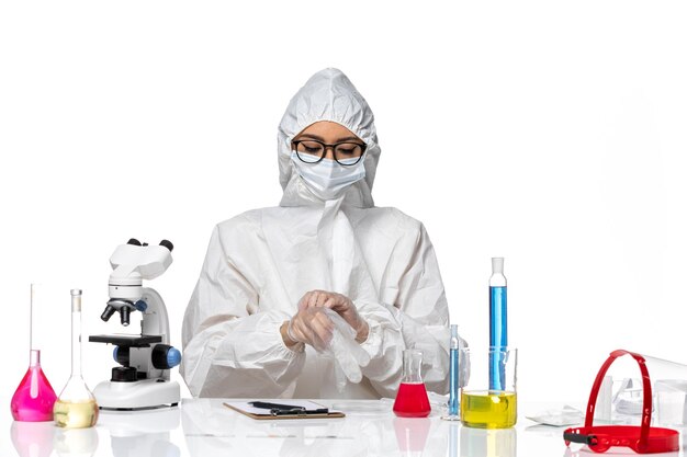 Química feminina em traje de proteção especial sentada de frente com soluções sobre o vírus covid da pandemia química
