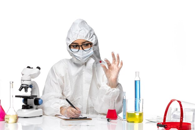 Química feminina em traje de proteção especial, verificando amostra em fundo branco, química de vírus covidêmica, vista frontal