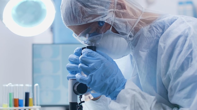 Químico cientista olhando para um microscópio médico, analisando uma amostra de DNA durante um experimento científico no laboratório de bioquímica. Médico pesquisador desenvolvendo vacina contra covid19. Conceito de medicina