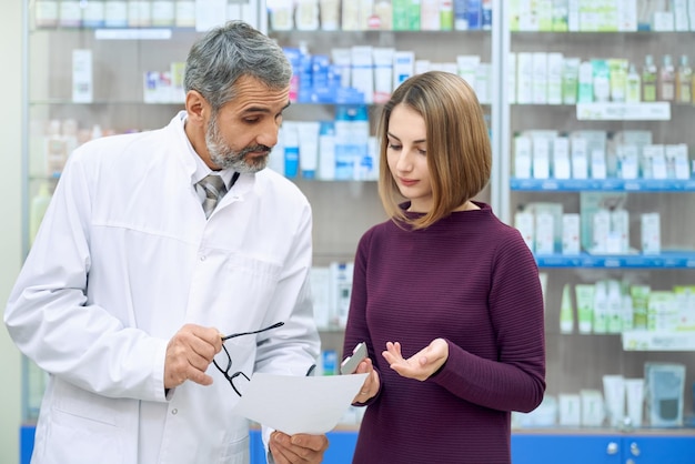 Químico explicando prescrição para mulher na farmácia