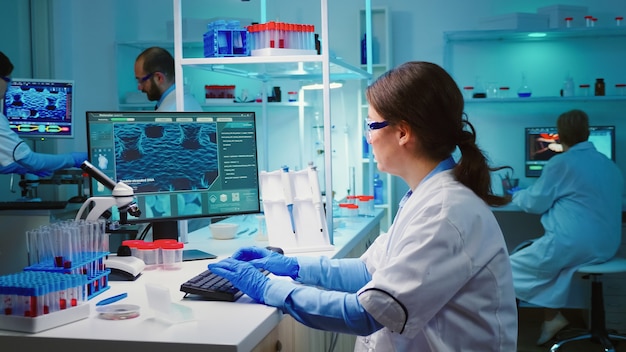 Químico sobrecarregado sentado em um laboratório equipado e moderno, parecendo cansado da câmera