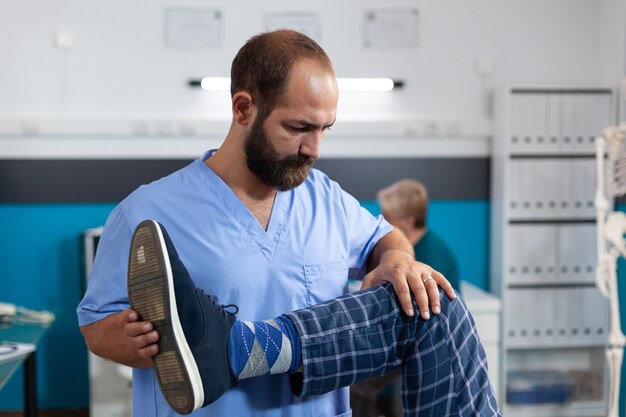 Quiroprático esticando a perna de um paciente idoso para fisioterapia