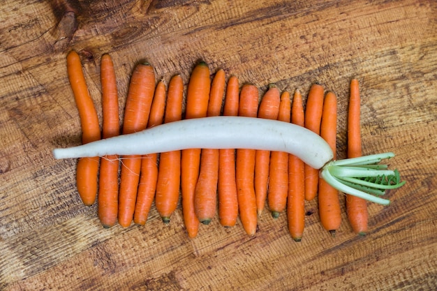 Rabanete de Daikon em cenouras, fundo de madeira