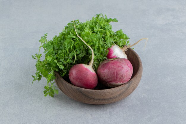 Rabanetes vermelhos e salsa em uma tigela, no mármore.