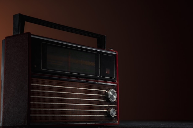 Rádio vermelho em fundo escuro. Perto de velhas coisas retrô filmadas com cores de estilo vintage e tonificadas.