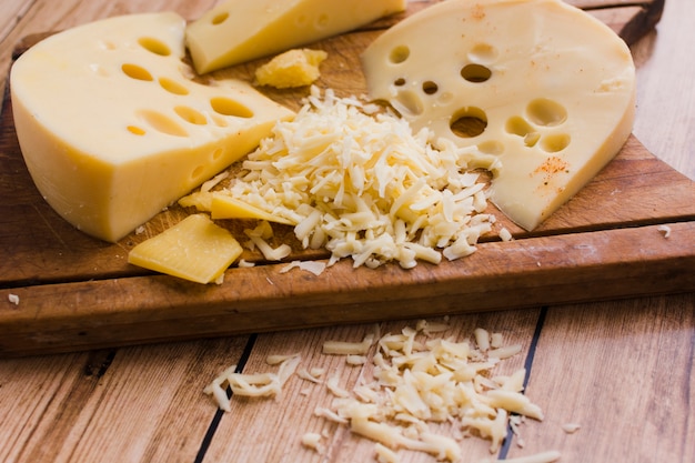 Foto grátis ralado e fatias de emmental na tábua sobre a mesa