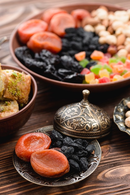 Ramadan secou frutas orgânicas cruas secas na placa metálica no pano de fundo texturizado de madeira