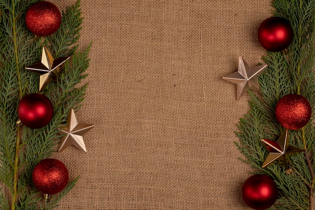 Foto grátis ramos de carvalho verde com bolas vermelhas de natal e estrelas douradas nos dois lados.