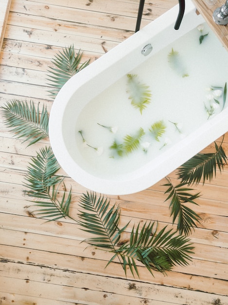 Foto grátis ramos de palmeira com vista superior de flores em uma banheira e em fundo de madeira