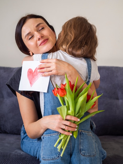 Rapariga adorável que abraça sua mãe