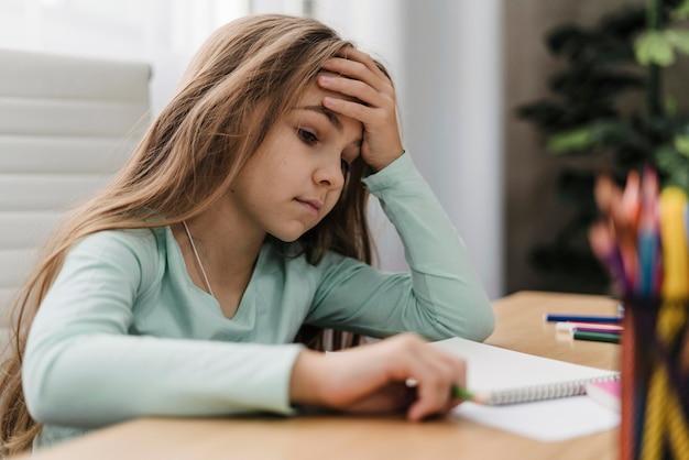 Rapariga com dor de cabeça enquanto dá aulas online