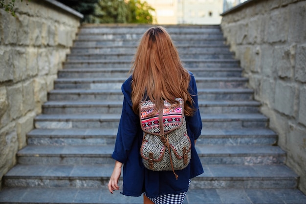 Rapariga estudante com uma mochila subir escadas