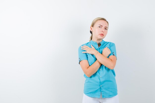 Rapariga loira com blusa azul, calça branca com dois braços cruzados isolados