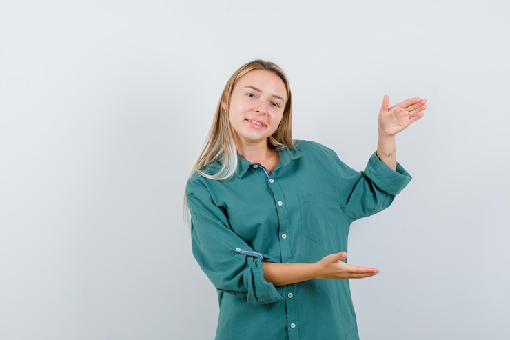 Foto grátis rapariga loira com blusa verde mostrando gesto de escalas e parecendo feliz