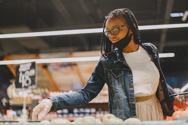 Rapariga negra com máscara a comprar comida