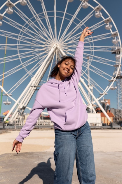 Rapariga sorridente com tiro médio no parque de diversões