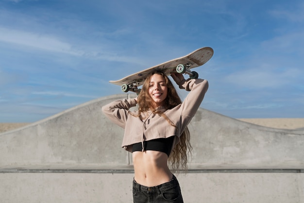 Foto grátis rapariga sorridente com tiro médio segurando um skate