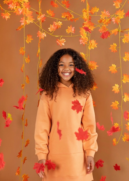 Rapariga sorridente de tiro médio a posar com folhas
