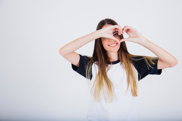 Foto grátis rapariga sorrindo e vendo através de um coração