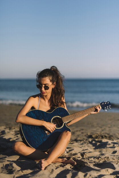 Rapariga tocando violão na praia