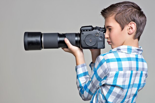 Rapaz adolescente com câmera dslr fotografando. Menino com câmera tirando fotos. Retrato do perfil.