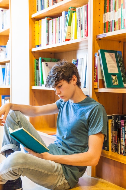 Rapaz adolescente lendo na biblioteca tranquila