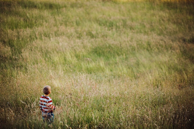 Rapaz pequeno corre no campo verde