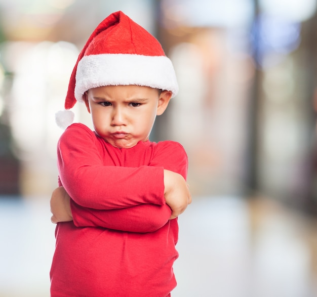 Rapaz pequeno irritado com chapéu de santa