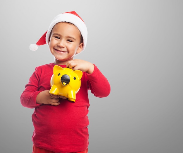 Rapaz pequeno que mostra seu piggybank amarelo