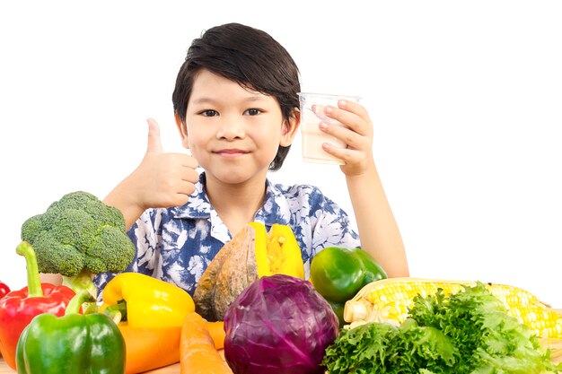 Rapaz saudável asiático mostrando expressão feliz com um copo de leite e variedade vegetal fresco