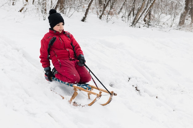 Rapaz solitário desfrutando de trenó andar no inverno