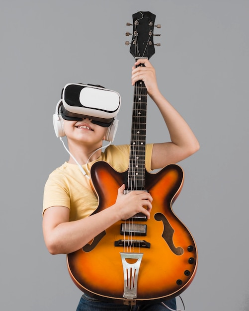 Foto grátis rapaz tocando guitarra enquanto estiver usando o fone de ouvido da realidade virtual