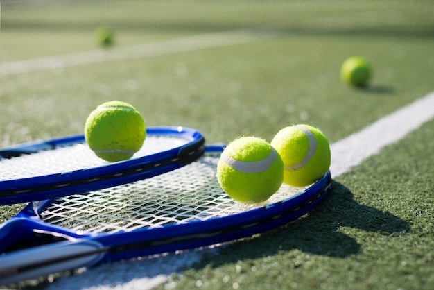 Raquetes de tênis de close-up e bolas no chão