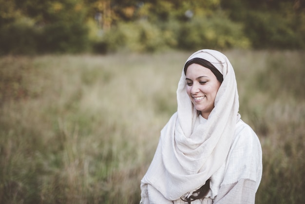 Raso foco tiro de uma mulher vestindo uma túnica bíblica e sorrindo