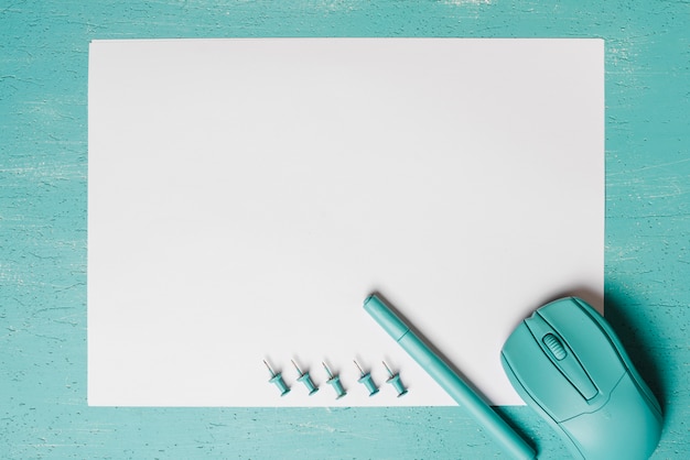 Foto grátis rato; caneta e alfinetes em papel branco contra fundo turquesa