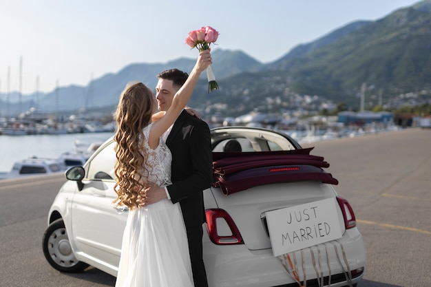 Foto grátis recém casados ao lado do pequeno carro