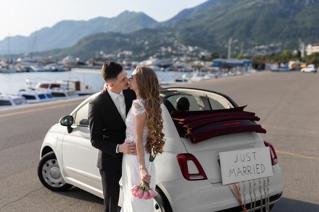 Recém casados ao lado do pequeno carro