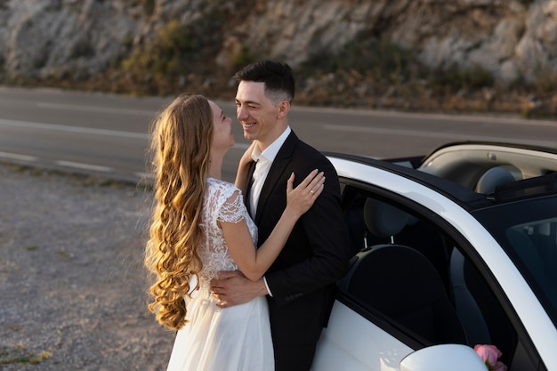 Recém casados ao lado do pequeno carro