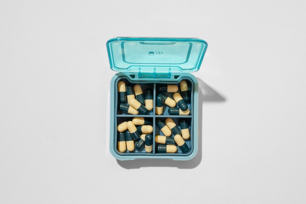Foto grátis recipiente de comprimidos na vista superior de fundo branco