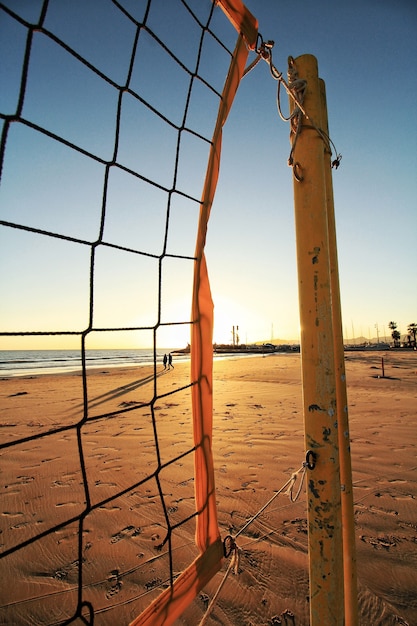 Foto grátis rede de vôlei na praia e o pôr do sol visto no fundo desfocado