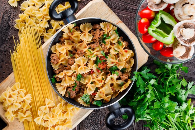 Refeição de macarrão na panela com macarrão cru, cogumelo, pimenta, salsa, tomate