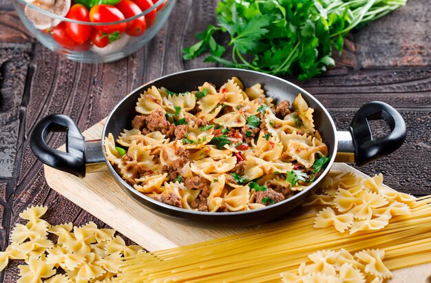 Refeição de macarrão na panela com macarrão cru, cogumelo, salsa, tomate